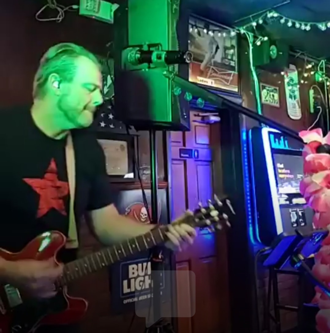 John D Parker playing guitar on stage with green lights